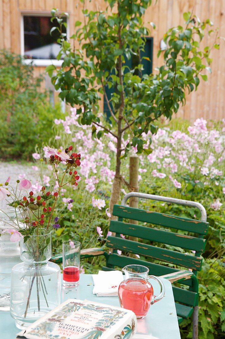Gedeckter Gartentisch im blühenden Sommergarten