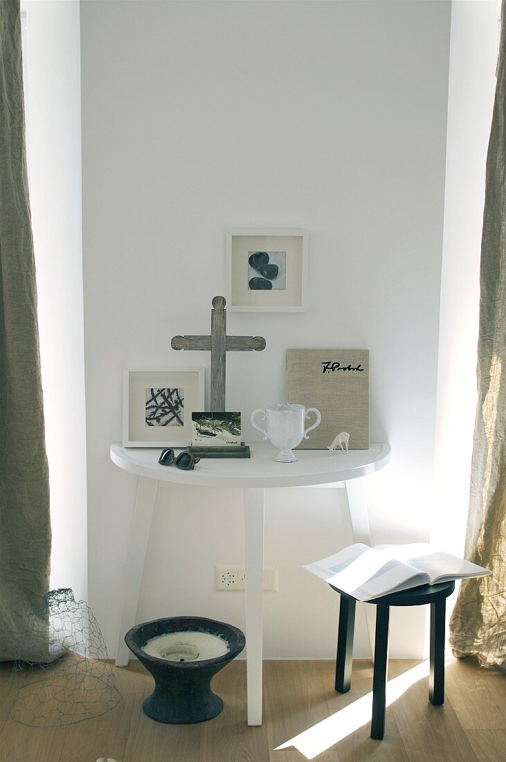 Pictures and ornaments on semi-circular table against white wall