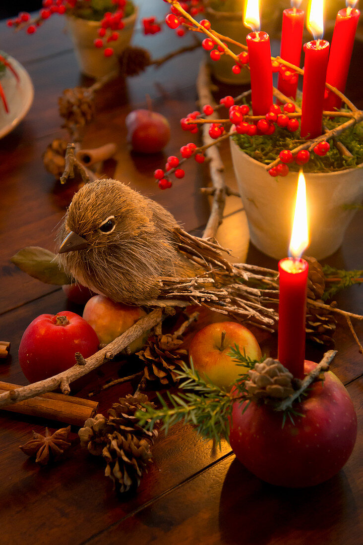 Dekovogel auf Lärchenzweig, Tontöpfchen mit Moos und Kerzen und Apfel mit Kerze als Weihnachtsdeko