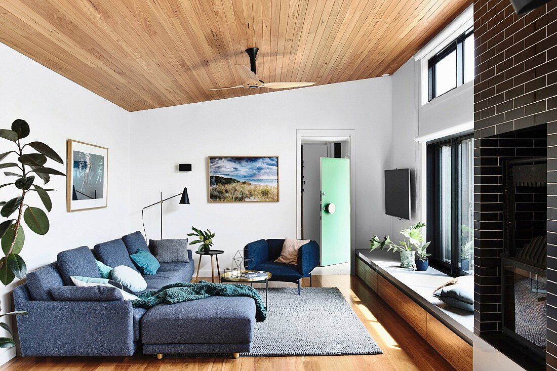 Loungebereich mit grauer Sofagarnitur, Fensterbank als Sitzbank und Holzdecke