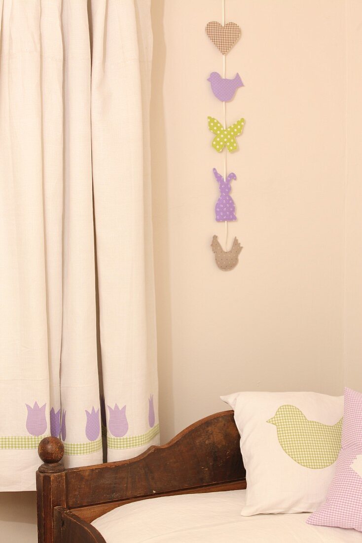 Girlande mit Ostermotiven an der Wand neben Vorhang mit Tulpenmotiv