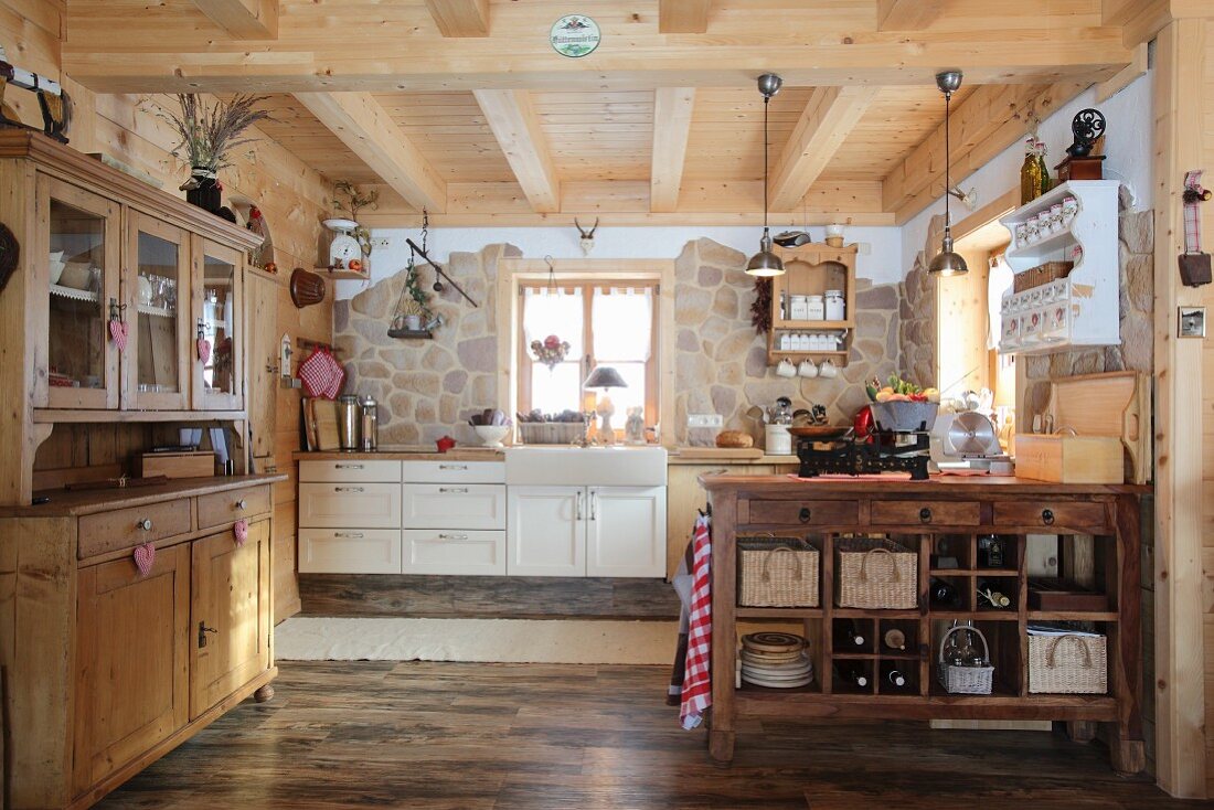 Offene Küche mit Anrichte, Küchenblock und teilweise Natursteinwand in einer Holzhütte