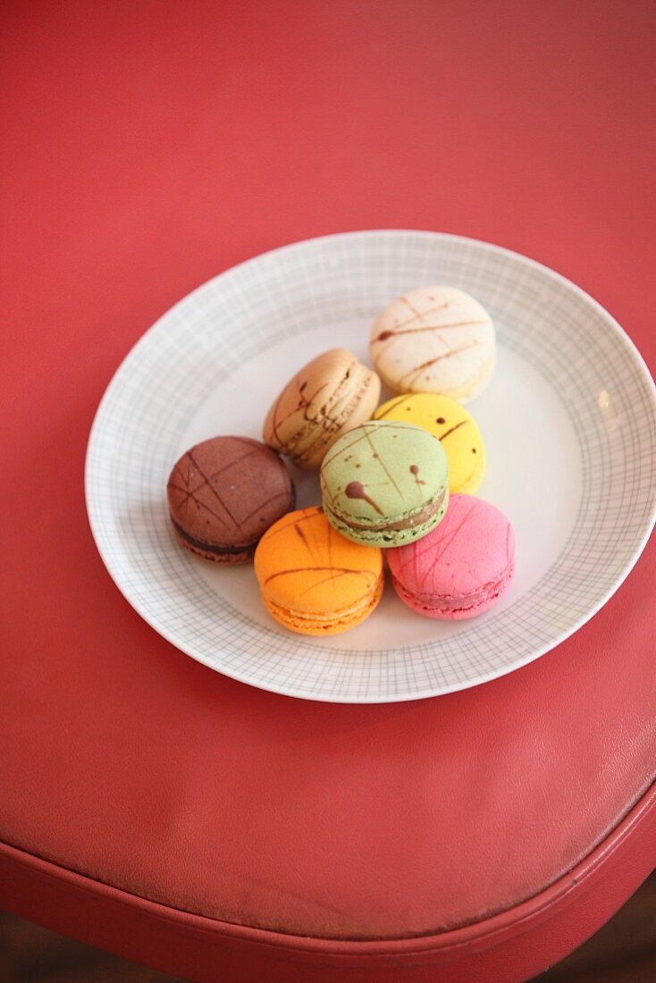 Plate of colourful macarons on red chair