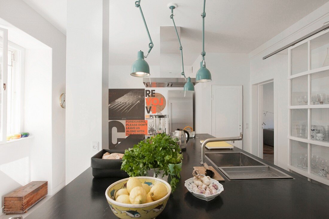 Schwarze Küchenarbeitsplatte mit Spülbecken und Armatur, darüber türkisfarbene Retro Leuchten