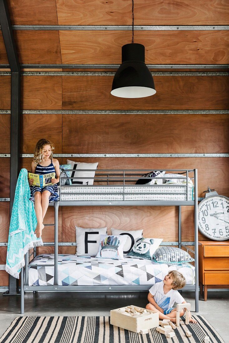 Etagenbett mit Metallgestell und Geschwister im Kinderzimmer mit Holzverkleidung