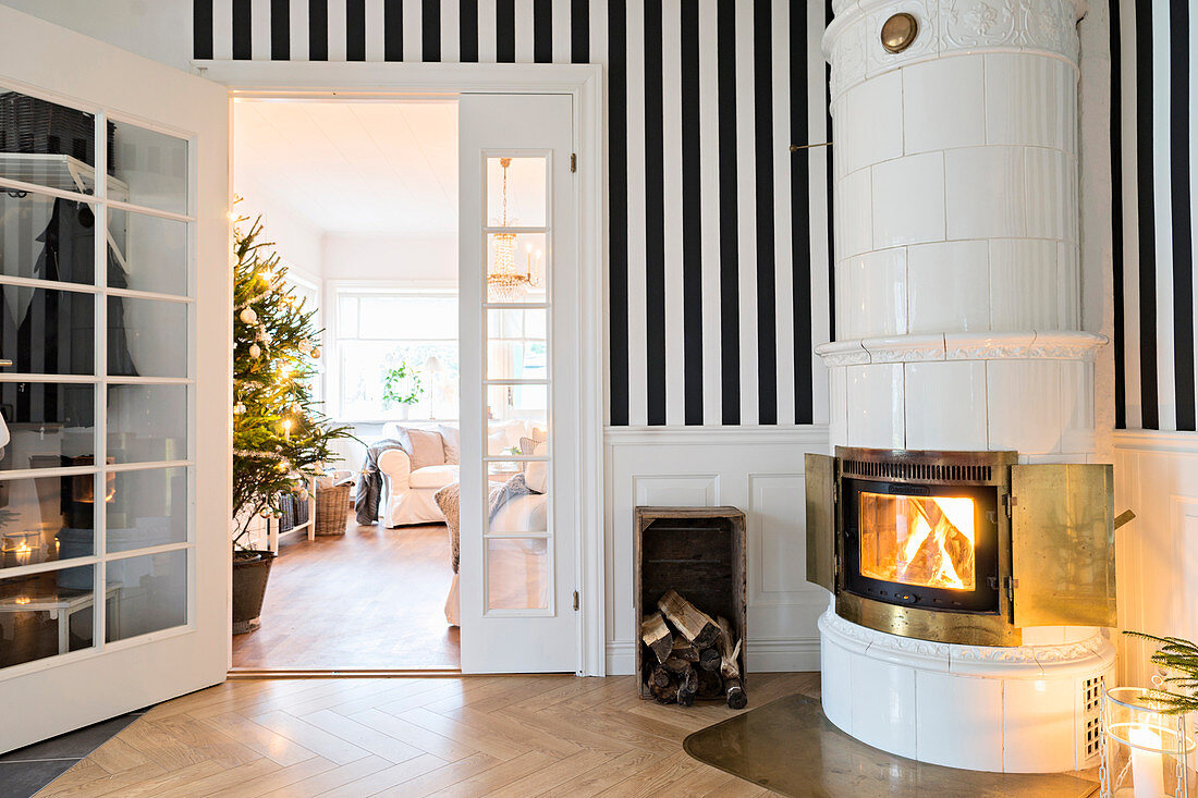 Fire lit in round tiled stove against striped wall