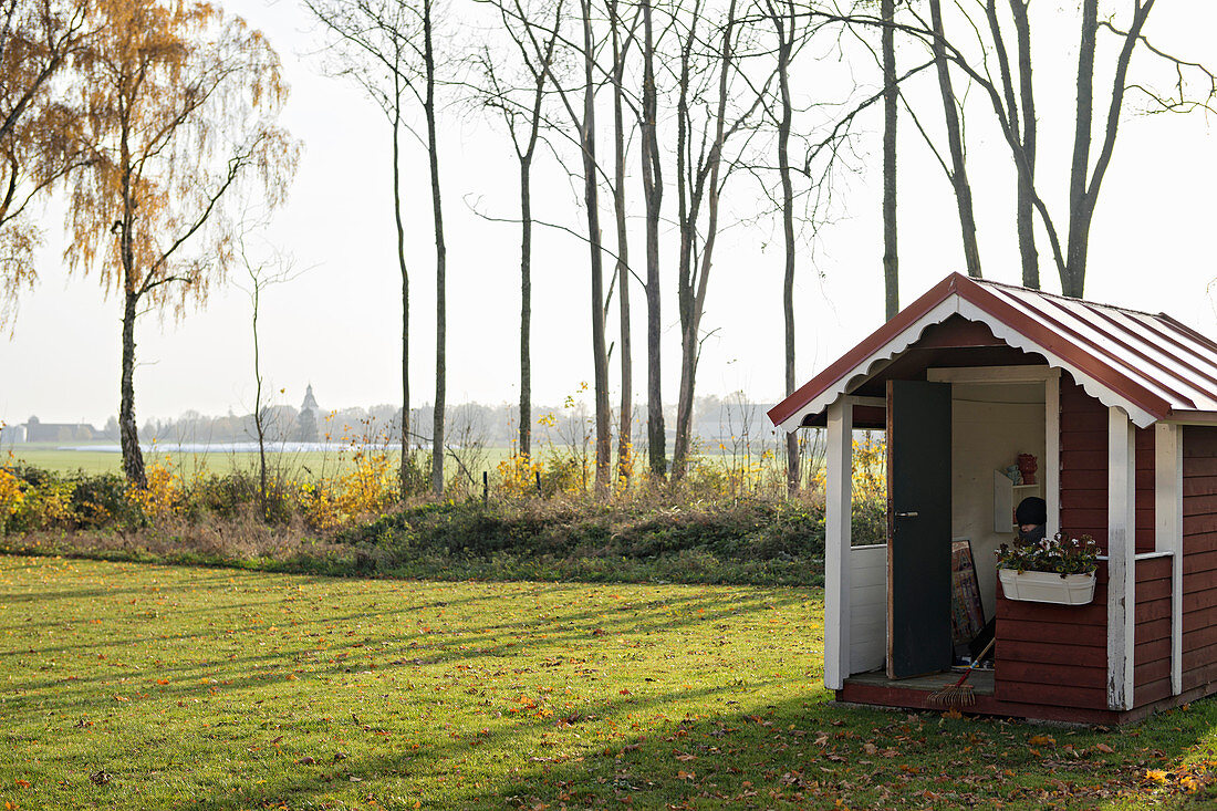 Swedish-style shed in large autumnal garden
