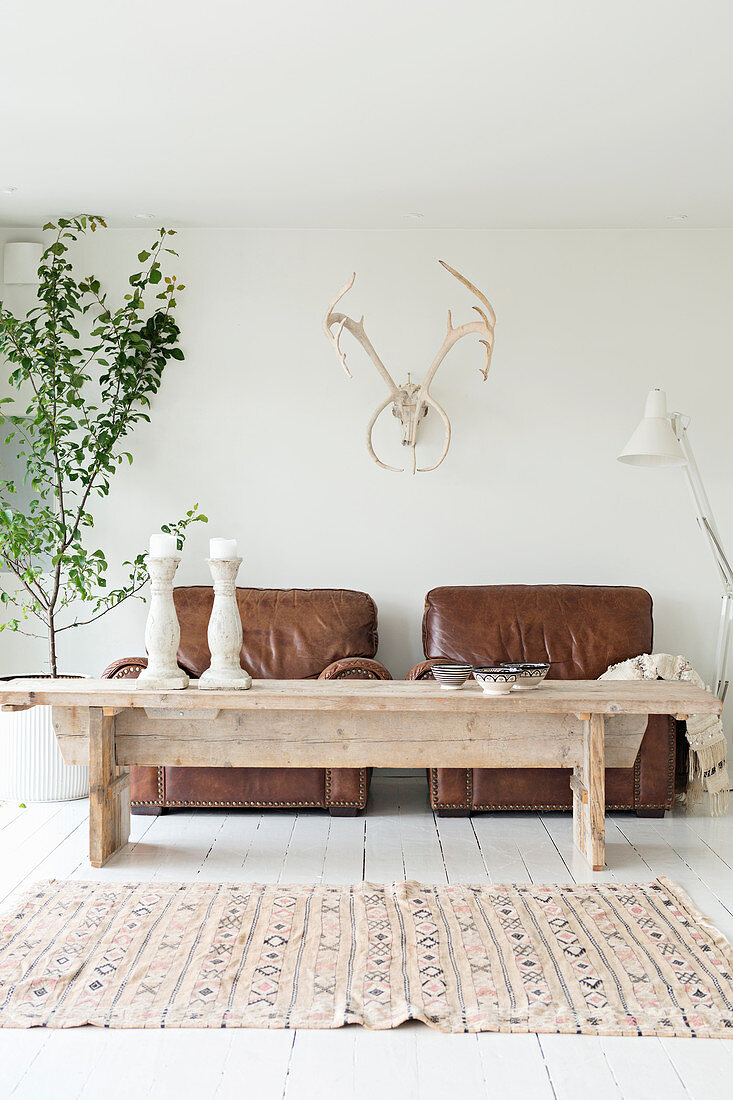 Rustic coffee table in front of two brown leather armchairs