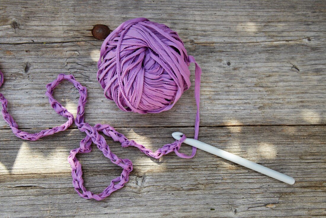 Row of chain stitch and ball of purple T-shirt yarn