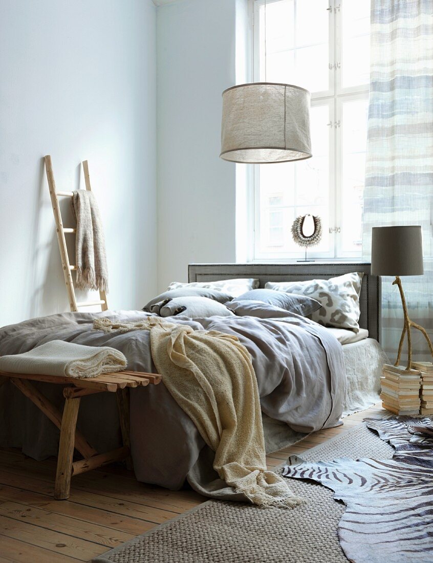Doppelbett im Schlafzimmer mit sandfarbenen Textilien und Treibholz Accessoires