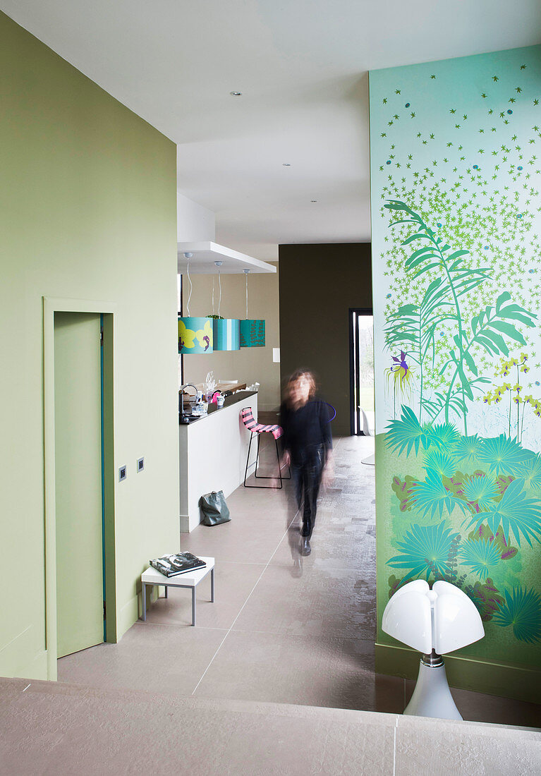 Frau geht durch offenen Wohnraum mit grünen Wänden