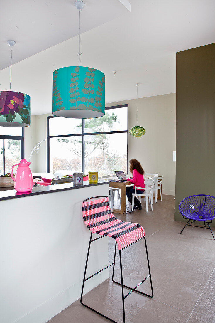 Woman working on laptop in open-plan kitchen-dining room with colourful accessories