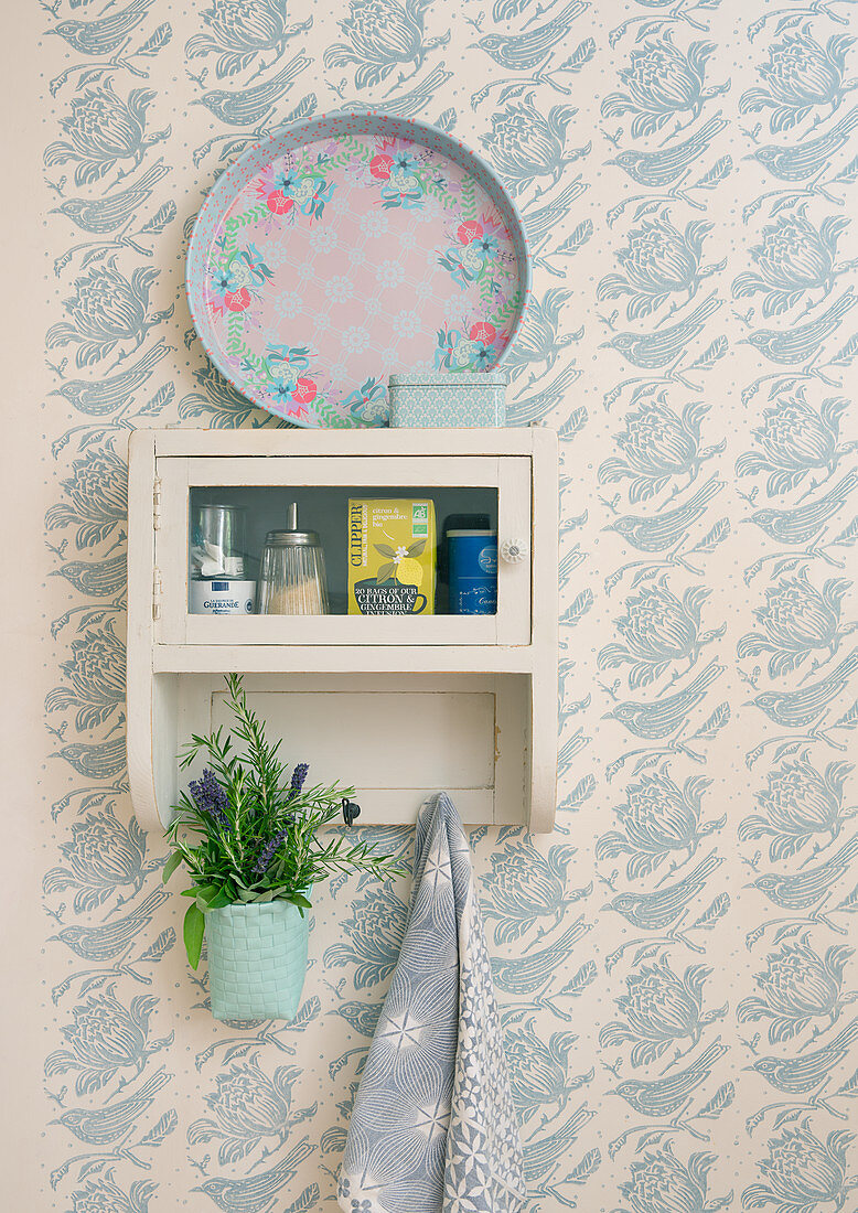 Pot of lavender hung from vintage kitchen cabinet on patterned wallpaper