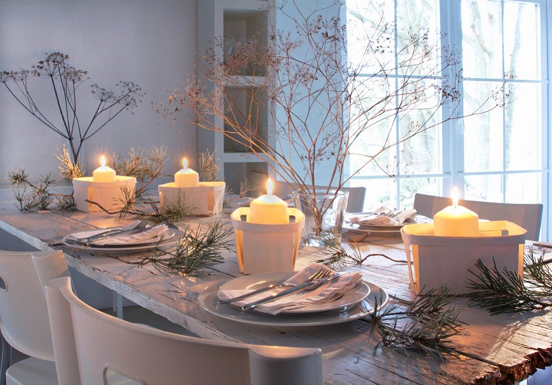 Winterliche, romantische Tischdekoration mit brennenden Kerzen in Spankörbchen