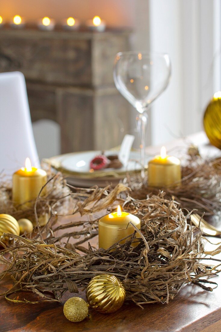 Festliche Tischdekoration mit getrockneten Kränzen und goldfarbenen Kerzen