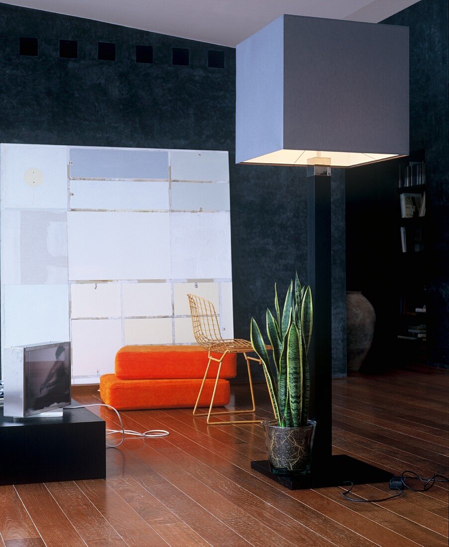 Standard lamp with cubist lampshade in front of orange floor cushions and modern artwork
