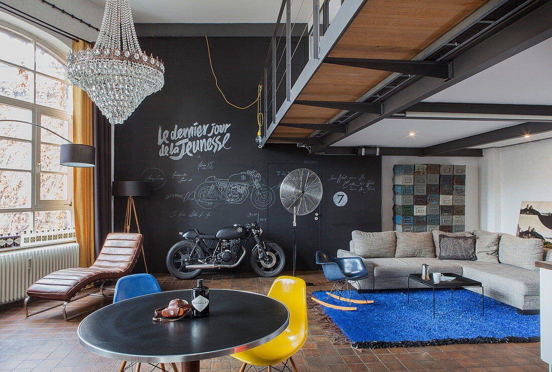 Offener Wohnraum im Loft mit schwarzer Wand und Designermöbeln