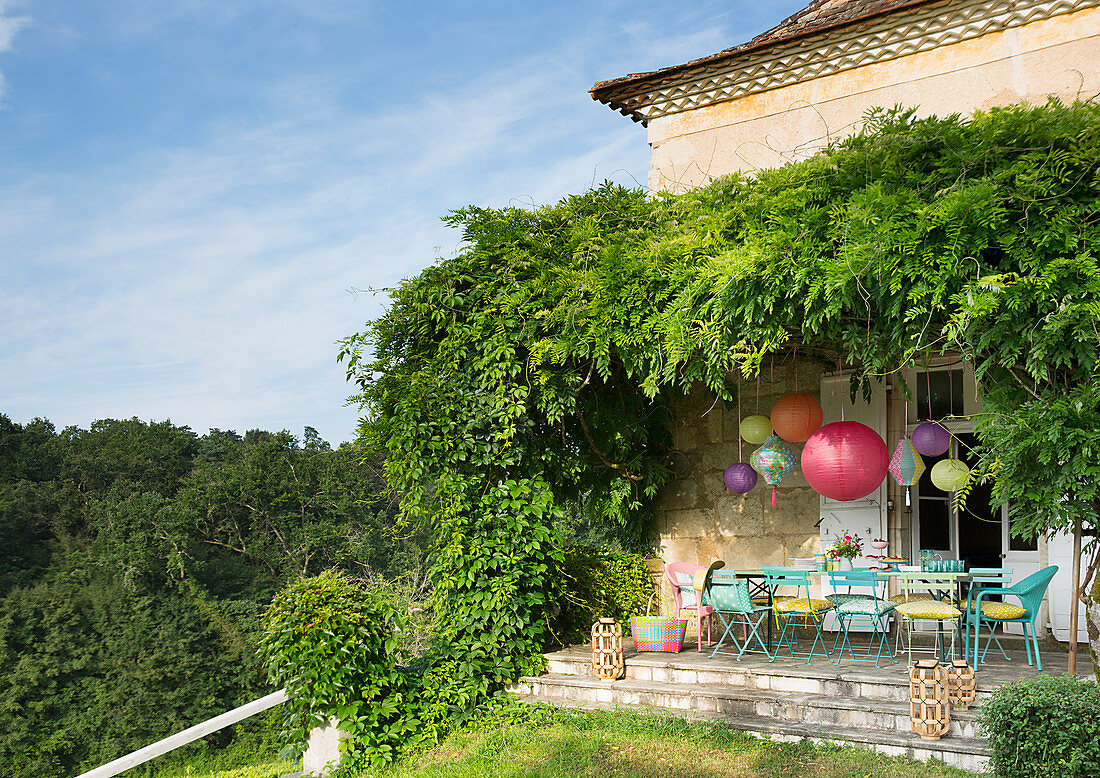 Bunt gestrichene Gartenstühle und Lampions auf der Terrasse