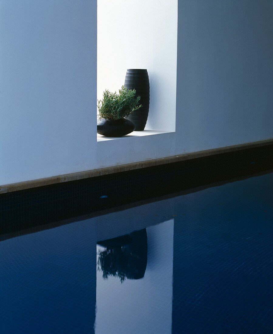 Zwei schwarze Vasen in einer Wandnische über dem Pool
