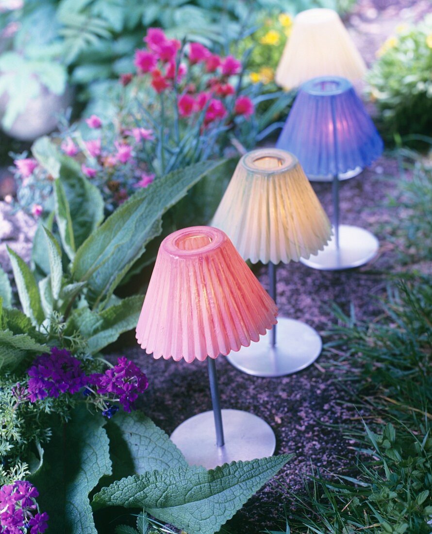 Teelichter mit verschiedenfarbigen Lampenschirmchen als sommerliche Gartendekoration