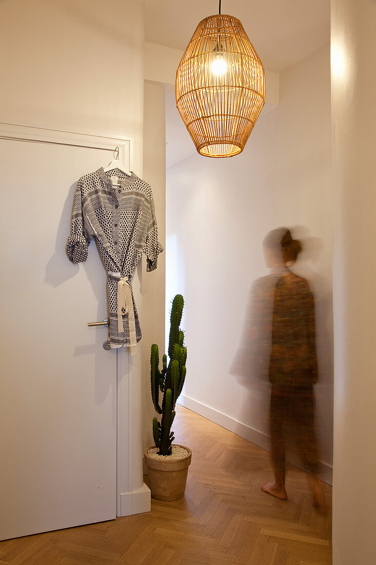 Woman walking along corridor with herringbone parquet floor and large cactus