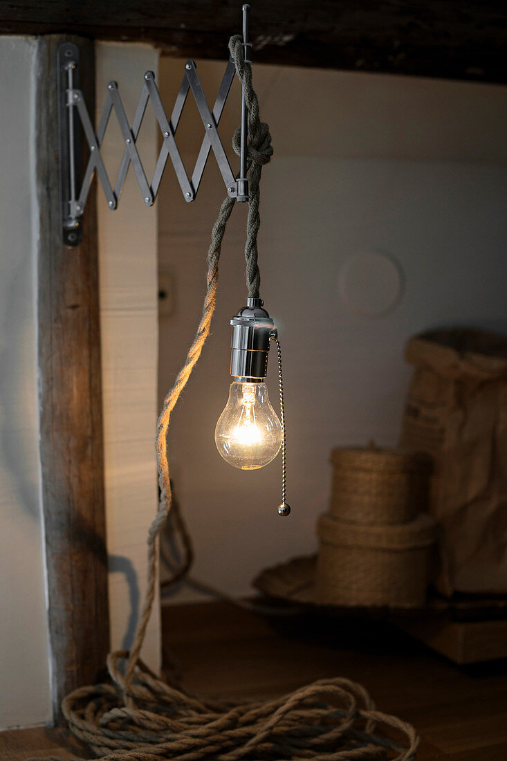 Light bulb hanging from chunky cord on vintage extending wall-bracket
