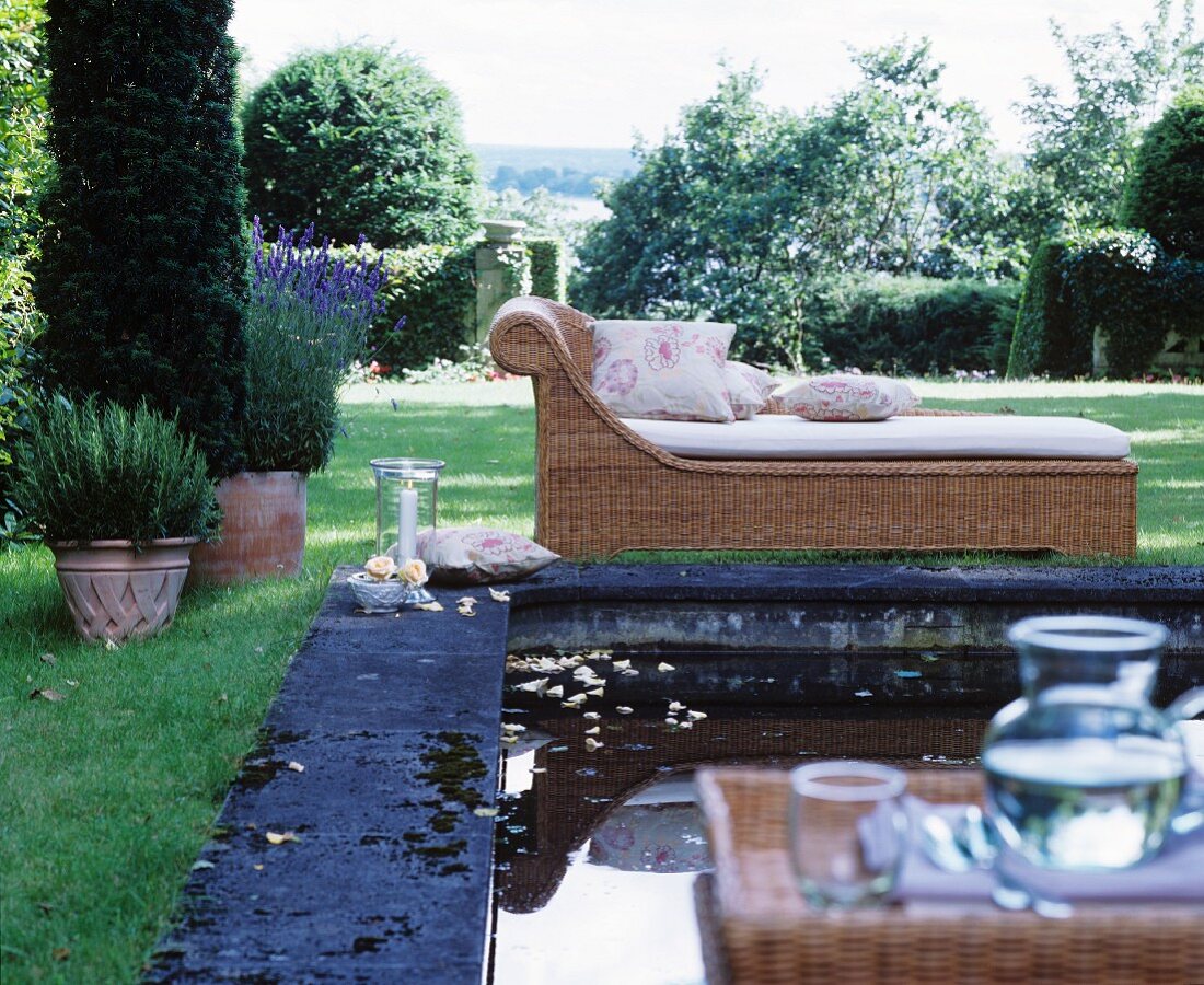 Wicker chaise longue next to pool in classic summer garden