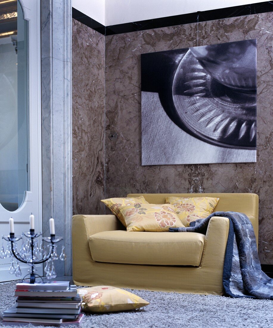 Senfgelbes Sofa unter moderner Fotografie vor einer Marmorwand