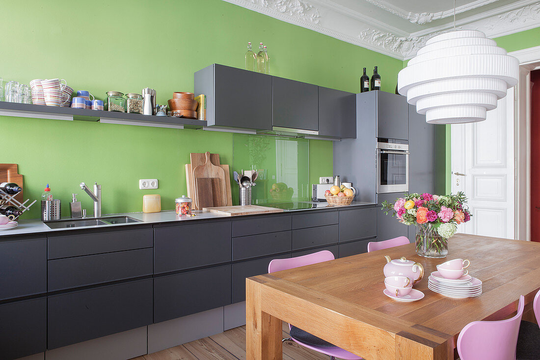 Esstisch in der grauen Küche mit grüner Wand und Stuckdecke