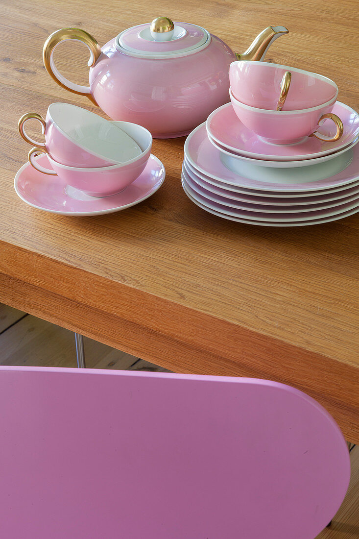 Rosafarbenes Teeservice gestapelt auf einem Holztisch