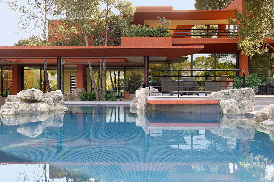 Swimming pool outside red, architect-designed house on multiple levels