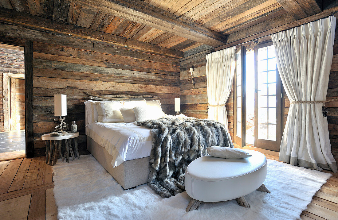 Bed on white fur rug in rustic bedroom