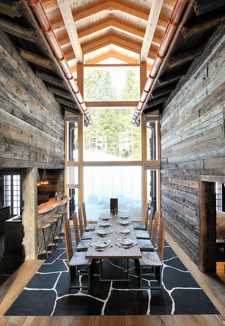 Long set dining table between two mountain huts incorporated into architect-designed house