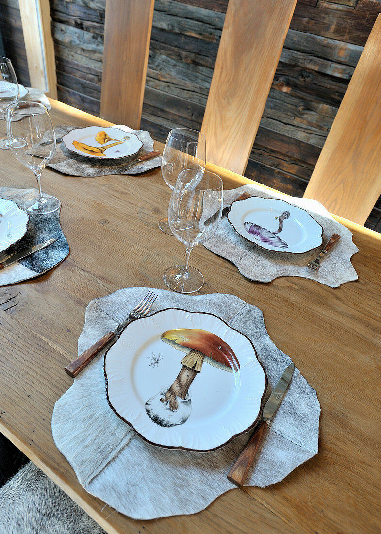 Teller mit Pilzmotiven und Tischsets aus Fell auf gedecktem Tisch