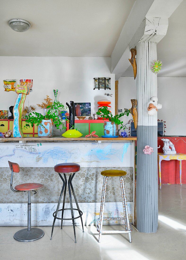 Breakfast bar, column and colourful eclectic furnishings in loft apartment