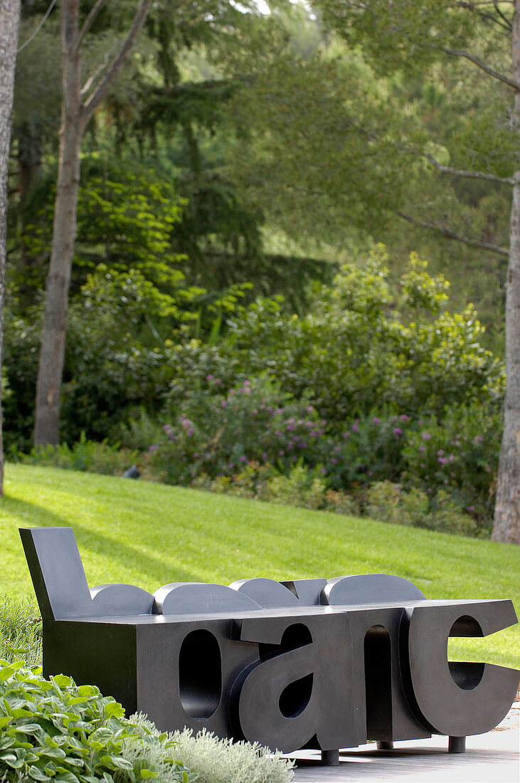 Künstlerische Sitzbank aus schwarzen Buchstaben im Garten