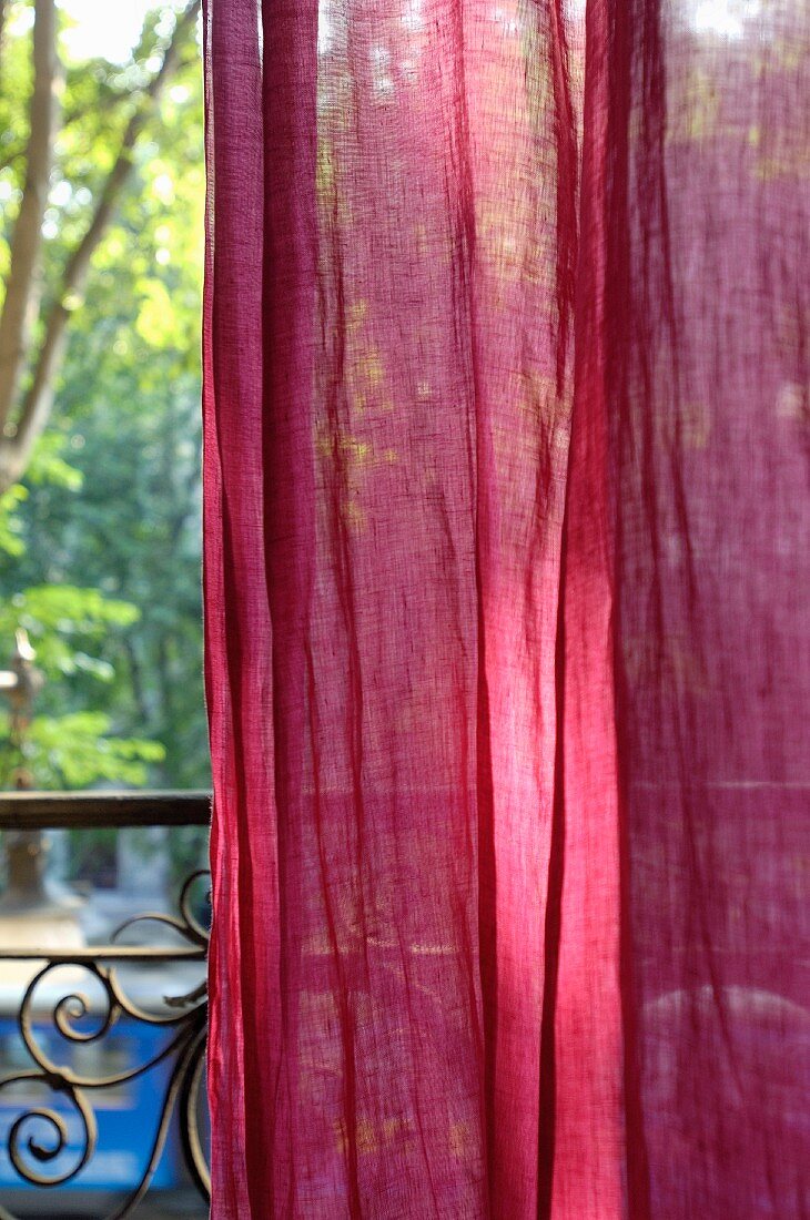 Red curtain in front of vintage-style balcony balustrade