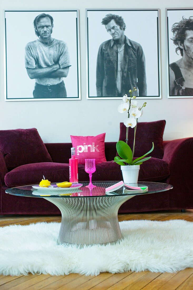 Round coffee table on sheepskin rug in front of purple sofa and pictures