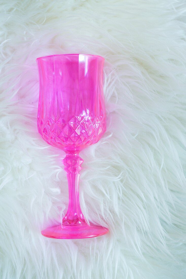 Pinkes Kristallglas liegt auf einem Schaffell