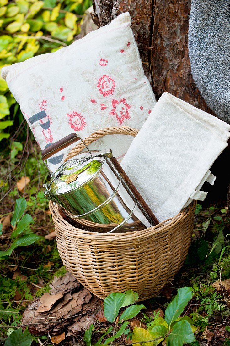 Cushions, tablecloth and tiffin box in picnic basket
