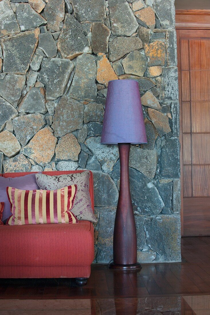 Sofa und Standleuchte vor einer Wand mit Natursteinverkleidung