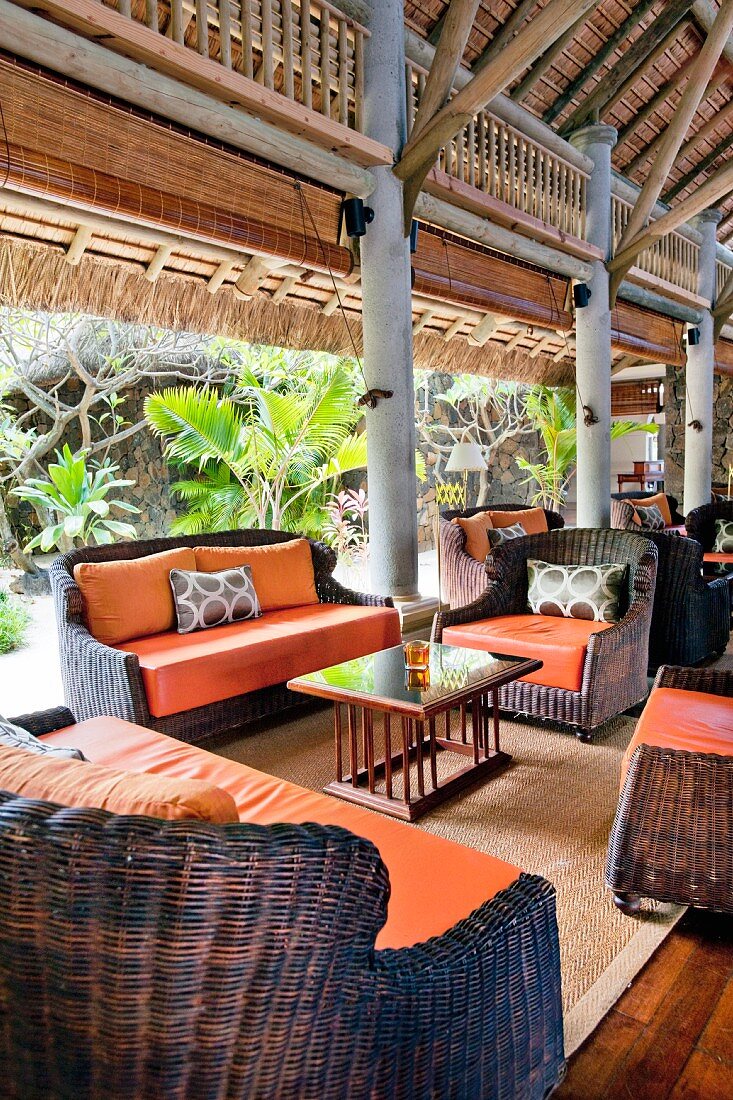 Exotische Lounge mit Korbstühlen und orangefarbenen Polstern