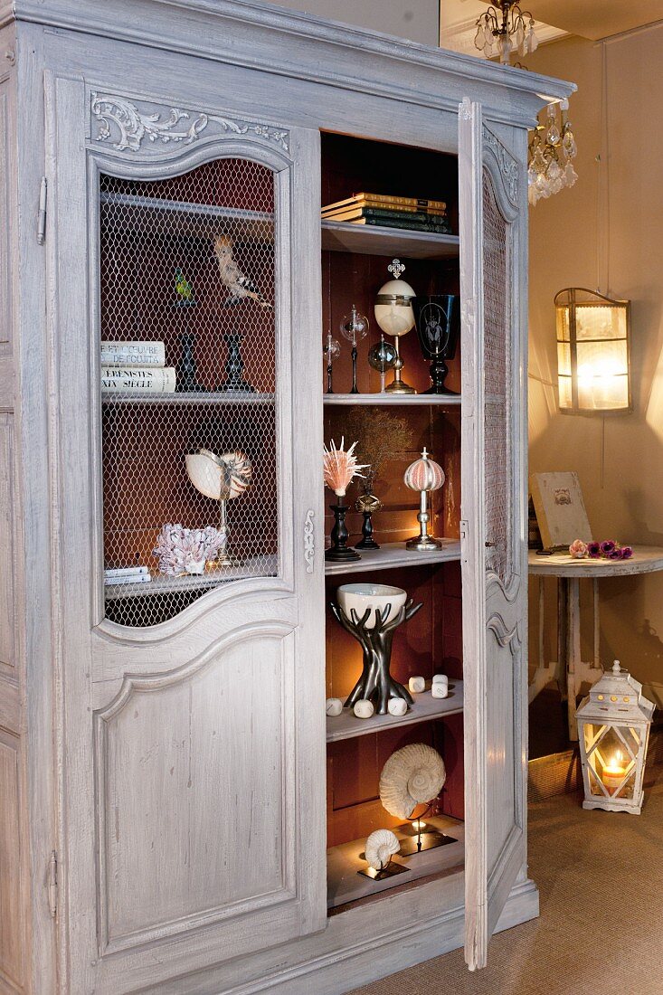 Various ornaments in antique wooden cupboard in vintage-style interior