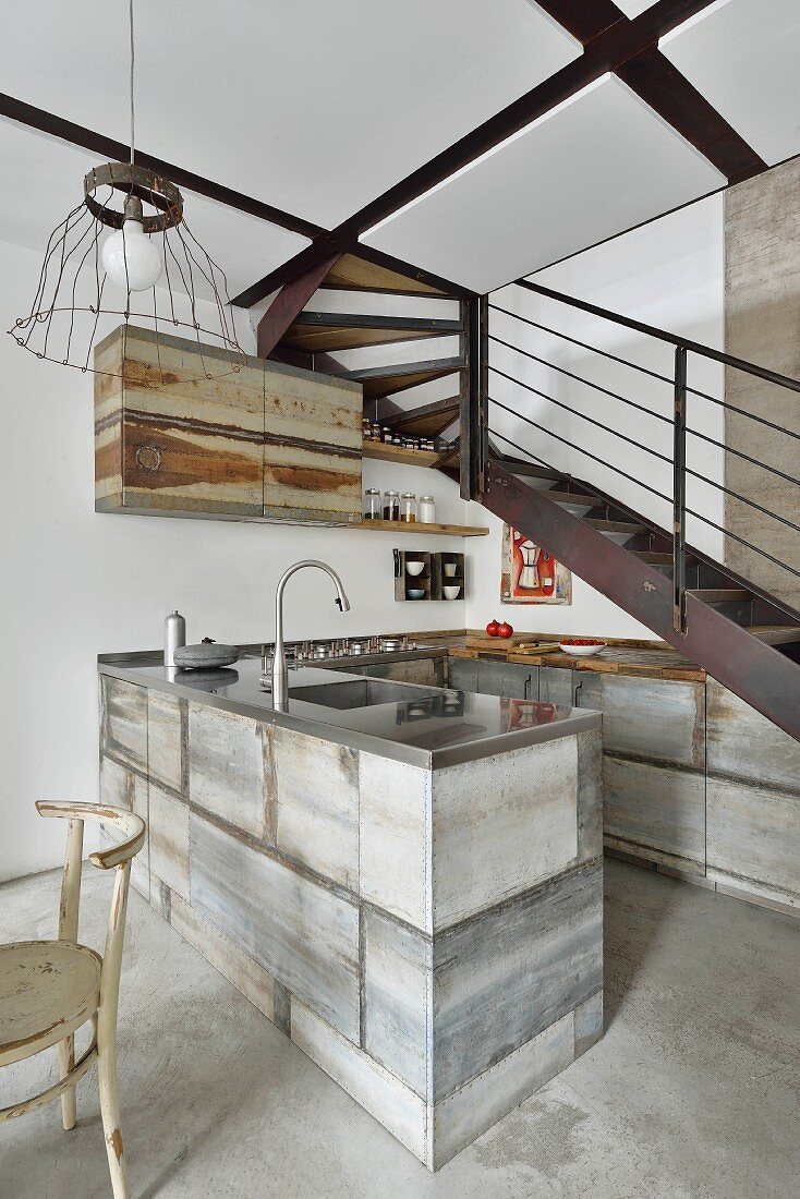 Rustic, industrial-style kitchen below metal staircase