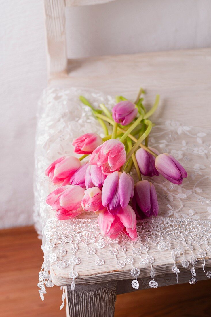 Pink and purple tulips and lace cloth on chair