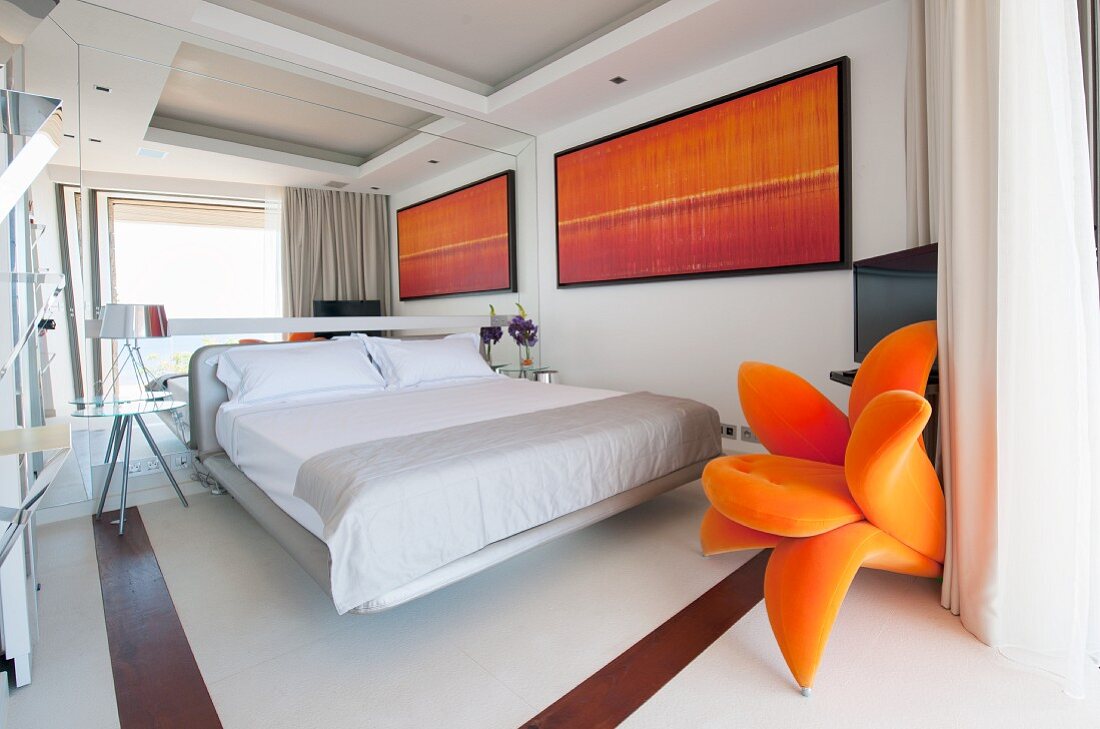 Schlafzimmer mit verspiegelter Wand und orangenen Akzenten