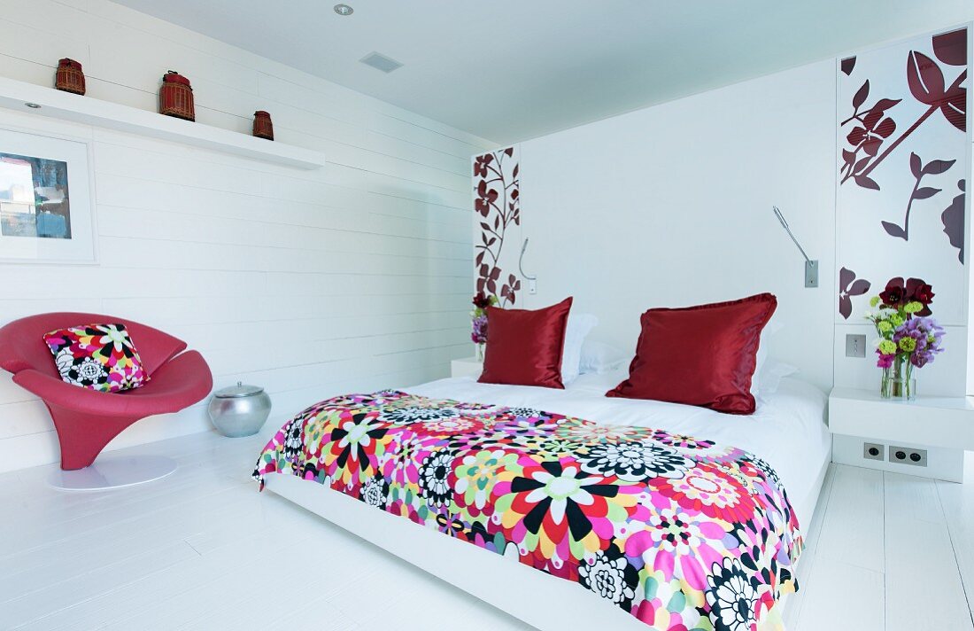Weißes Schlafzimmer mit roten Farbakzenten und Blumenmuster
