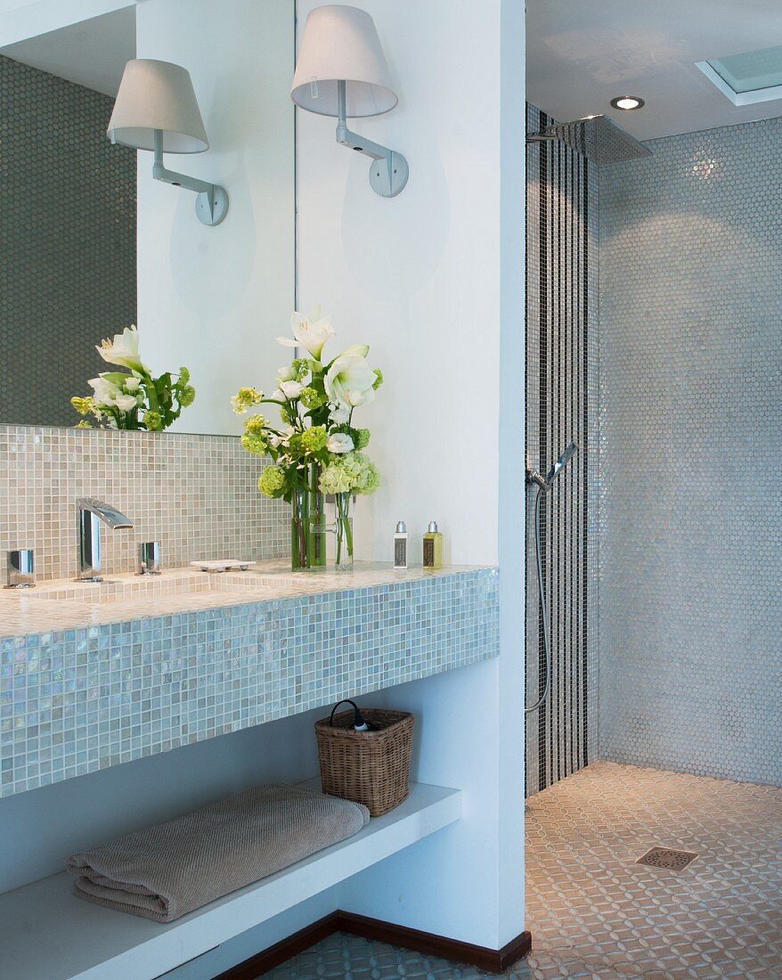 Mosaic tiles, open shower area and fresh flowers in bathroom