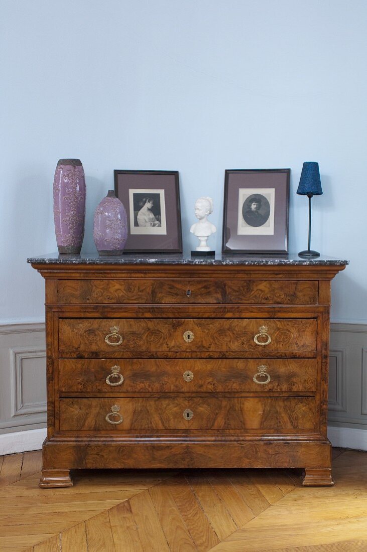 Antique burl chest of drawers with marble top against blue wall
