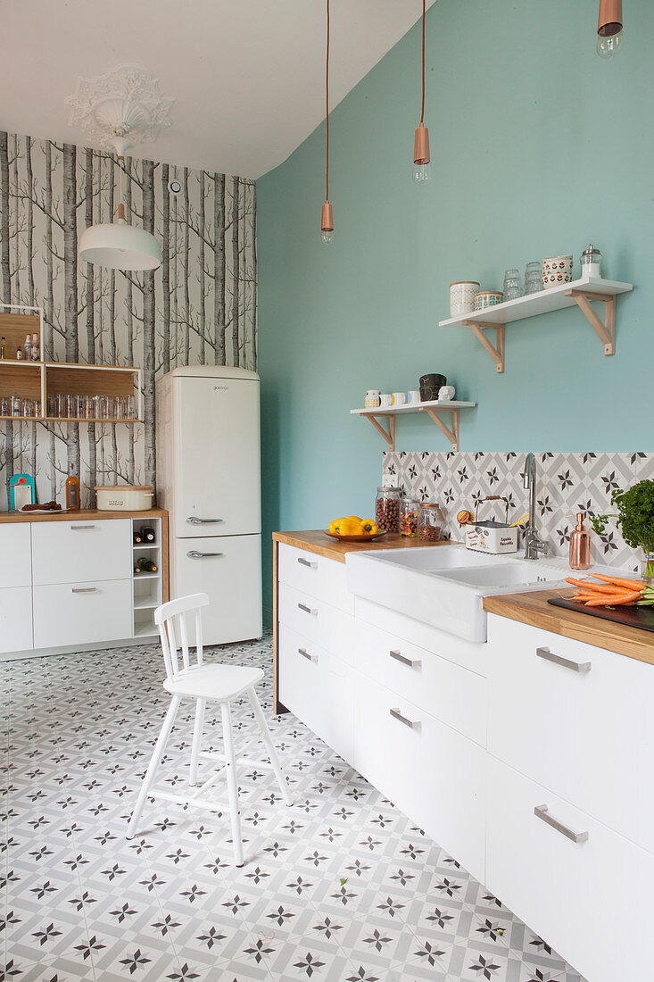 Küche mit weissen Schrankfronten, hellblauer Wand und gemusterten Zementfliesen